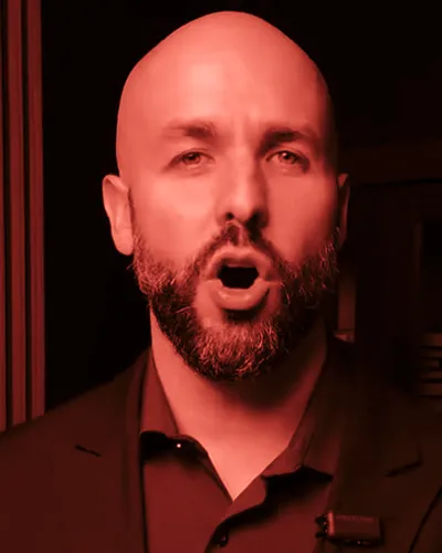 Frame from Ryan Caracciolo’s 2026 campaign video: Caracciolo mid-word, mouth open, in a dark jacket and maroon shirt.